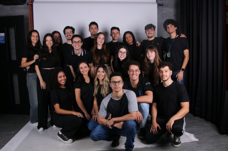 Foto de grupo dos membros da gestão 23.2 da PUC Consultoria Jr., vestidos de preto em um estúdio fotográfico.