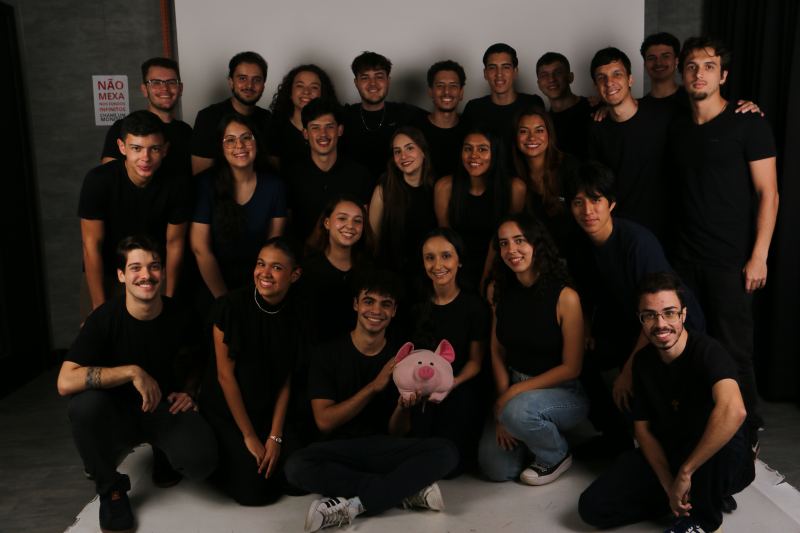 Foto de grupo dos membros da gestão 25.1 da PUC Consultoria Jr., vestidos de preto em um estúdio fotográfico.