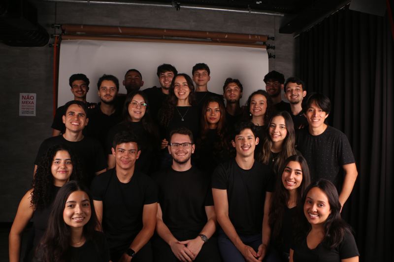 Foto de grupo dos membros da gestão 25.2 da PUC Consultoria Jr., vestidos de preto em um estúdio fotográfico.