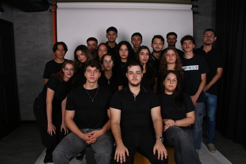 Foto de grupo dos membros da gestão 26.1 da PUC Consultoria Jr., vestidos de preto em um estúdio fotográfico.